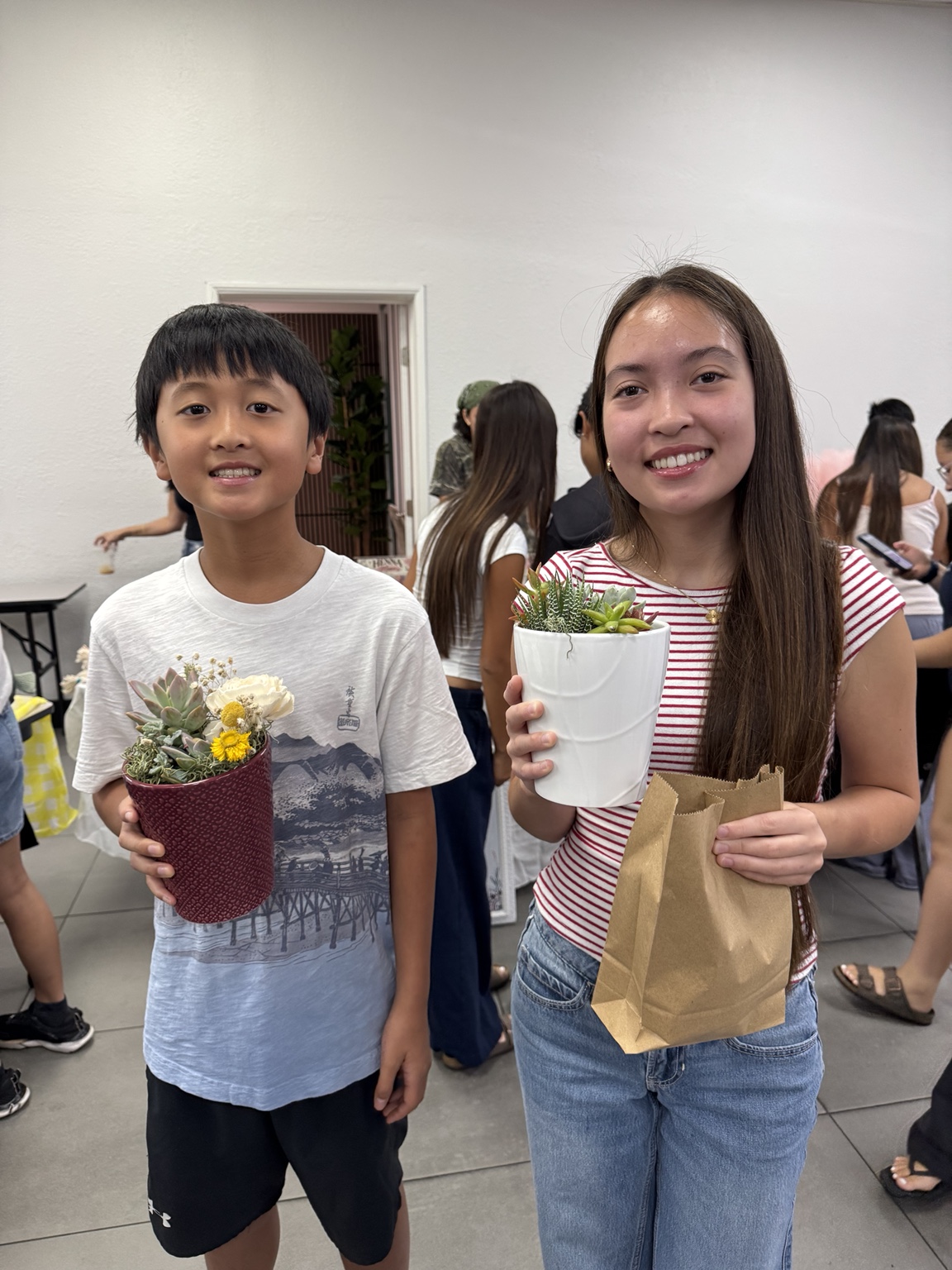 Winston smiling with a customer holding two WillWin ReBloom succulent arrangements